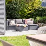 Garten mit grauem Sitzmöbelset und grüner Umgebung.