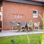 Terrasse mit Tisch, Stühlen und Sonnenschutz vor Backsteinhaus