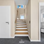 Hallway with wooden stairs, bathroom, and door