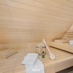 Sauna with wooden bench, bucket, shovel, and towels.