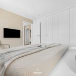 Bedroom with bed, wardrobe, and TV mounted on the wall.
