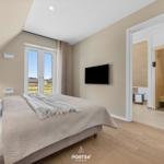 Bedroom with bed, window, and TV. Sauna visible next.