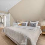 Bedroom with sloped ceiling, bed, nightstand, and wardrobe.