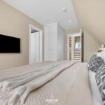 Bedroom with bed, TV, and wardrobe. Attic with staircase.