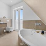 Bathroom with bathtub, sink, and toilet under a sloped ceiling.