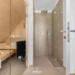 Sauna with wooden benches and shower with glass wall