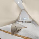 Bedroom with sloped ceiling, bed with white bedding and patterned blanket.