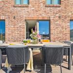Terrace with table and chairs in front of brick house