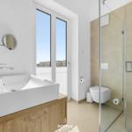 Bathroom with shower, toilet, and sink with window view.