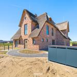 Modern brick building with thatched roof and round entrance area.