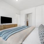 Bedroom with bed, TV, and closet. Wall with pattern. Duvet and pillow with patterns.