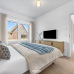 Bedroom with bed, TV, and view of thatched roofs through window.
