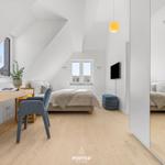 Bedroom with sloped ceilings, bed, desk, and windows.