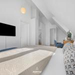 Bedroom with sloped ceiling, bed, TV, and seating area.