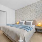 Bedroom with bed, nightstand, and patterned wallpaper.
