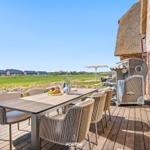Terrace with table and chairs, view of fields and buildings.