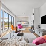 Wohnzimmer mit großem Fenster, Sofa, Fernseher und Kamin.