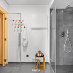 Dusche mit Regenduschkopf, Sauna und Handtuchständer mit bunten Haken.