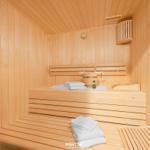 Sauna mit Holzbank, Handtuch und Thermometer an der Wand.