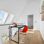 Schlafzimmer mit Dachfenstern, Schreibtisch und roter Stuhl.