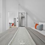 Schlafzimmer mit Dachschräge, Bett mit Kissen und TV an der Wand.