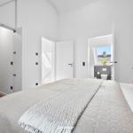 Schlafzimmer mit Bett, Kleiderschrank und Blick auf Bad.