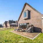 Haus mit Dach aus Stroh und Terrasse mit Sitzgelegenheiten.