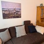 Ein braunes Sofa mit Kissen steht vor einer Wand mit einem großen Bild.