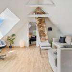 Living area with sofa, chair, and wooden floor under sloped ceilings.