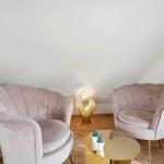Two pink chairs and a round table are in the room with wooden floor.