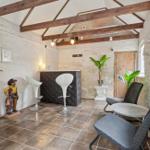 Room with wooden beams, bar stools, plants, and seating by window