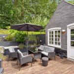 Terrace with seating, umbrella, and plants. Black facade and white windows.