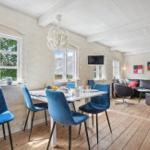 Dining area with blue chairs and living room with sofa and TV.