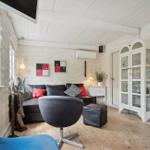 Living room with sofa, seating and glass cabinet. Wooden floor and large windows.