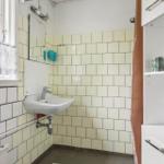 Bathroom with sink, mirror, and window. Wall tiles and cabinet visible.