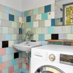 Bathroom with washing machine and colorful tiles on the walls.