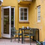 Patio with table, two chairs, and open door to the house.