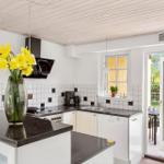 Kitchen with black countertops, white cabinets, and window to the garden.