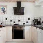Kitchen with white cabinets, dark countertop, and oven. Wall with tiles and poster.