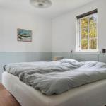 Bedroom with bed, two windows, and wall pictures.