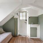 Room with bed, window, standing lamp, and small wash area with sink.