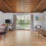Room with wooden ceiling, dining area, and living area with garden view