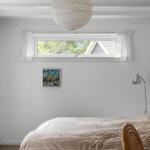 Bedroom with bed, windows, and ceiling lamp.
