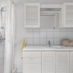 Bathroom with shower, sink, and white cabinets.