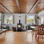 Living and dining area with fireplace, wooden floor, and windows.