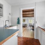 Kitchen with worktop and view into living room with wooden floor and ceiling beams.