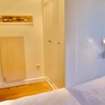 Schlafzimmer mit Bett, Wandlampe und Kleiderschrank.