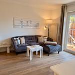 Wohnzimmer mit Sofa, Kamin und Blick auf die Terrasse.
