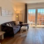 Wohnzimmer mit Sofa, Tisch und Terrassentür. Holzboden und Wandbild.