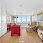 Living room with red armchair, side table, and window view of the landscape.